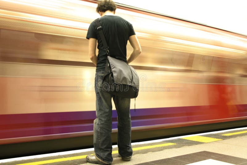 Treno in movimento veloce davanti a un giovane uomo.