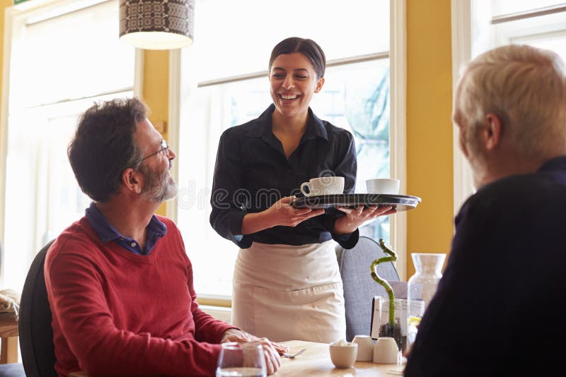 Waitress bringing coffees to a male couple at a restaurant