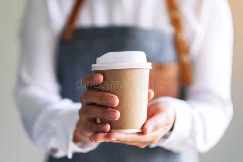 A waitress holding and serving a paper cup of hot coffee