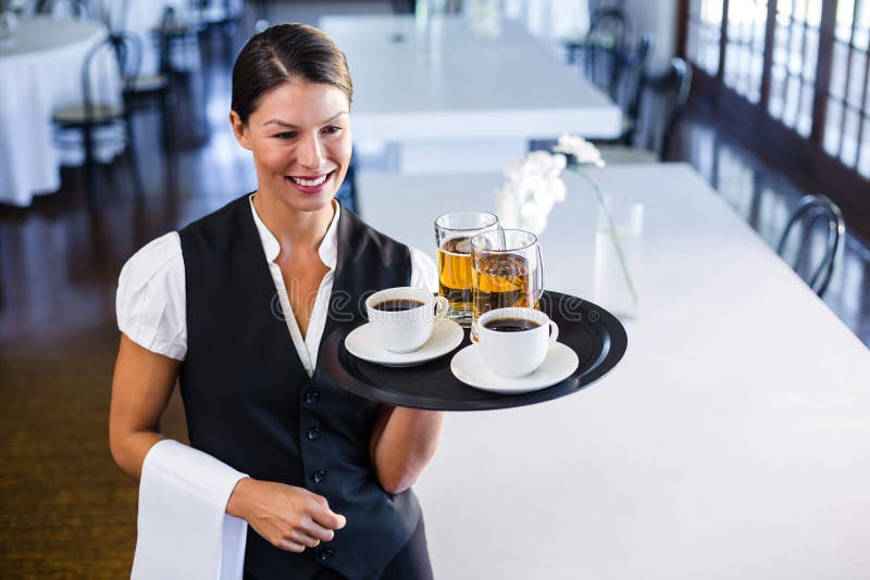 Waitress holding serving tray with coffee cup and pint of beer. 
