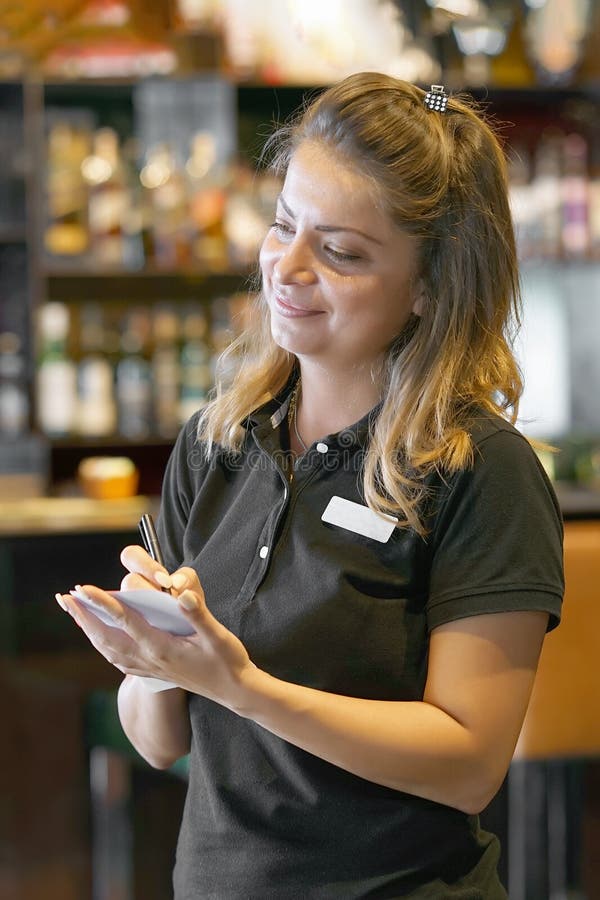 Smiling waitress taking an order in a restaurant. Adult, lifestyle.
