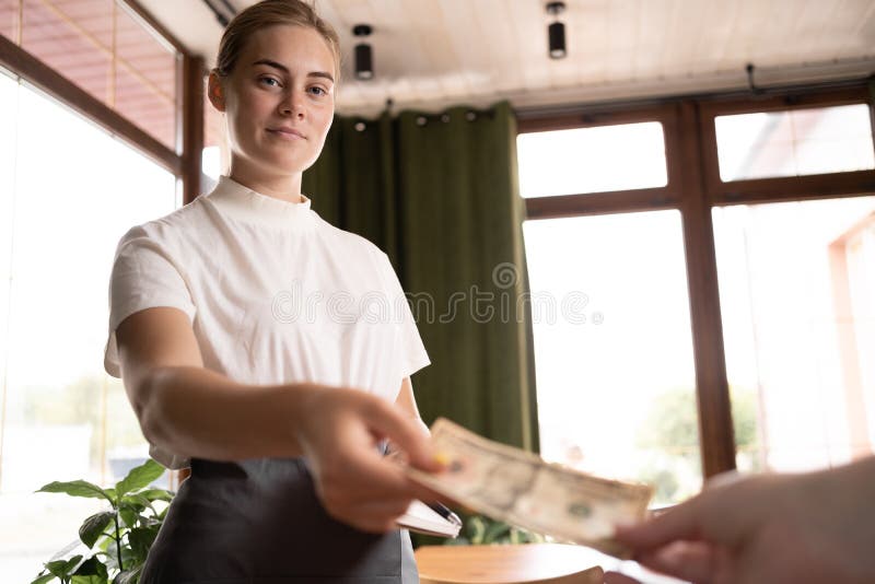 Waitress takes the tip. The waiter female receives a tip from the client at the cafe or restaurant. Service