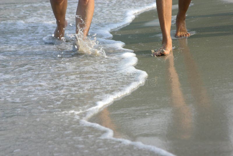 Un'immagine di una coppia gambe camminano fianco a fianco lungo il bordo delle acque.