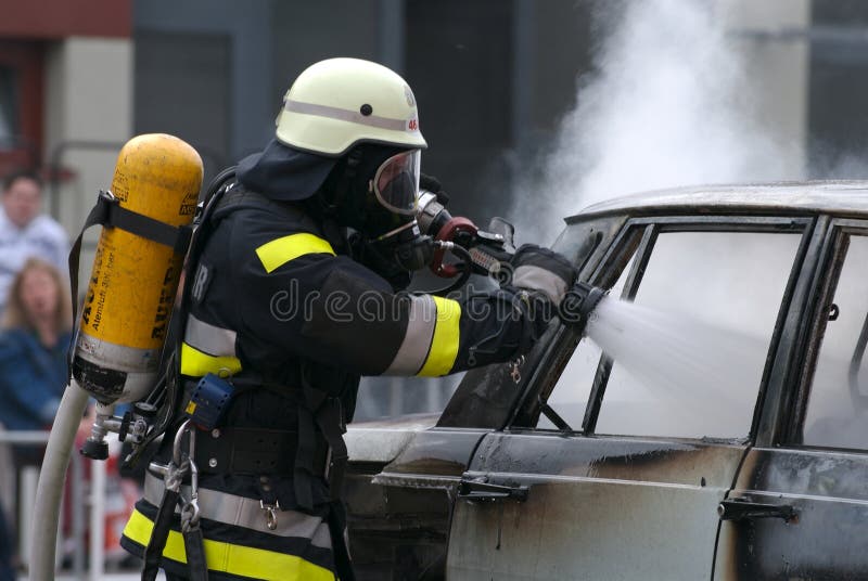A fire-fighter works at a burning car. A fire-fighter works at a burning car