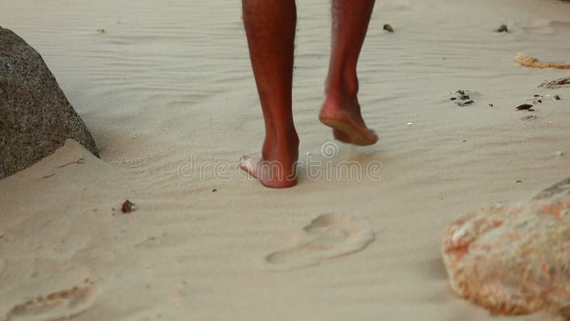 Walkers feet on a white sandy beach with rocks dry