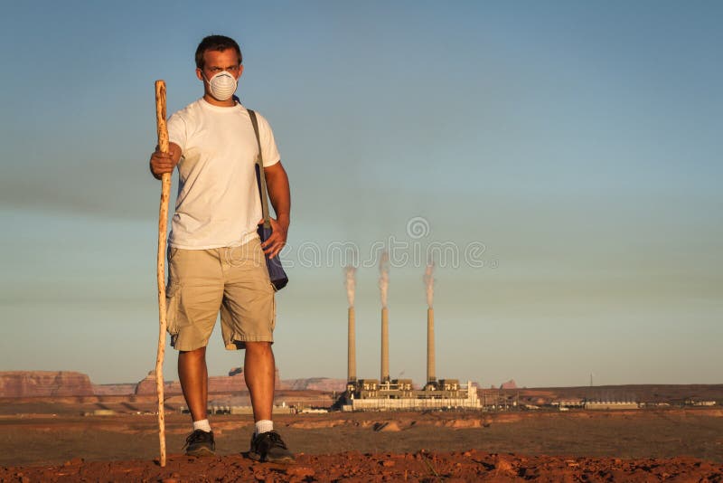 Il concetto di immagine di un uomo che indossa una maschera e un bastone da passeggio a piedi dalla combustione del carbone centrale elettrica con sporco di fumo nell'aria.