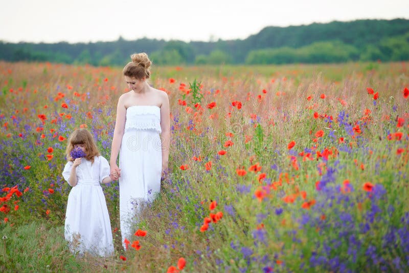 The Eldest Daughter Walks Down The Flower Path Walking Mother and Daughter with Flowers. Summer Day Walk Across Stock
