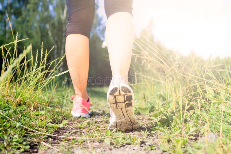 O correr ejercicio, piernas sobre el césped verde acera en Bosque, éxito idoneidad aventura a ejercicio en la primavera o verano naturaleza.