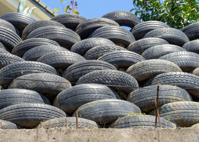 Wall of old tires. Unusual decoration of the land. Wheel fence. Penetration protection