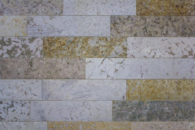 Wall of Rectangular White, Gray, Yellow Marble Tiles. Rough Surface