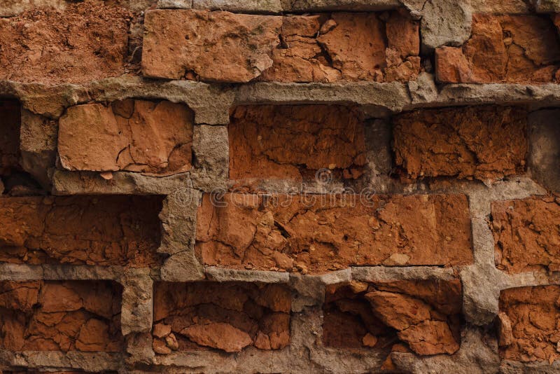 The wall of red dilapidated brick. The ruined brick wall close-up. Facade of a destroyed brick building. Pattern, texture, backgro