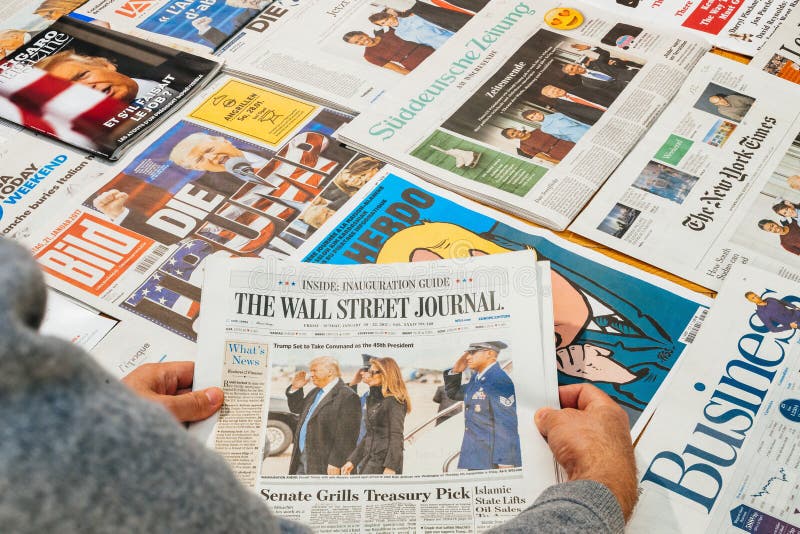 PARIS, FRANCE - JAN 21, 2017: Man holding The Wall Street Journal above major international newspaper journalism featuring headlines with Donald Trump, Barack Obama, Melania Trump and Michele Obama inauguration as the 45th President of the United States in Washington, D.C. PARIS, FRANCE - JAN 21, 2017: Man holding The Wall Street Journal above major international newspaper journalism featuring headlines with Donald Trump, Barack Obama, Melania Trump and Michele Obama inauguration as the 45th President of the United States in Washington, D.C