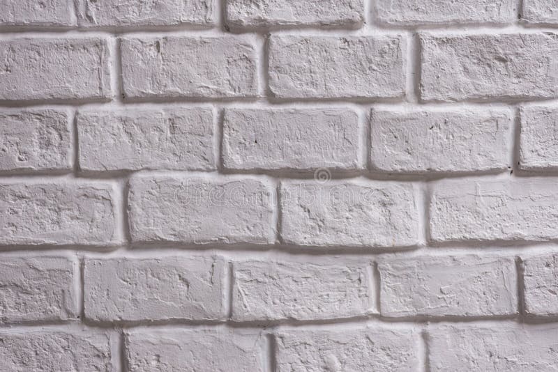 A wall of white brick aging by time and faded by wheather. A stone work and background for house design