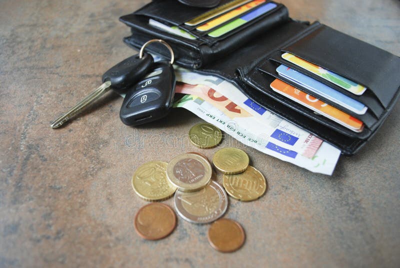 Wallet with cash, cards, car keys on the table.