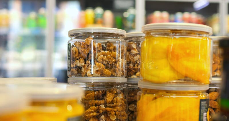 Walnuts and dried mango slices are displayed in clear jars on a supermarket shelf, offering a healthy and convenient stock photos