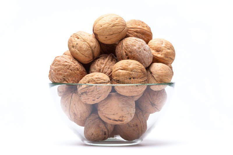 Walnuts lie in a glass bowl isolated on white