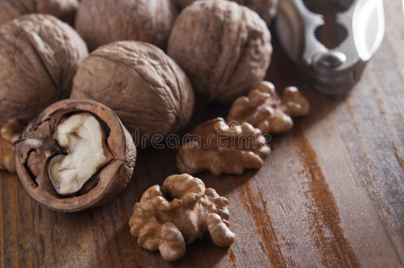 Walnuts peeled and inshell. In the background is a nutcracker. Brown wooden table. Close-up royalty free stock photography Walnuts peeled and inshell. In the background is a nutcracker. Brown wooden table. Close-up royalty free stock photography