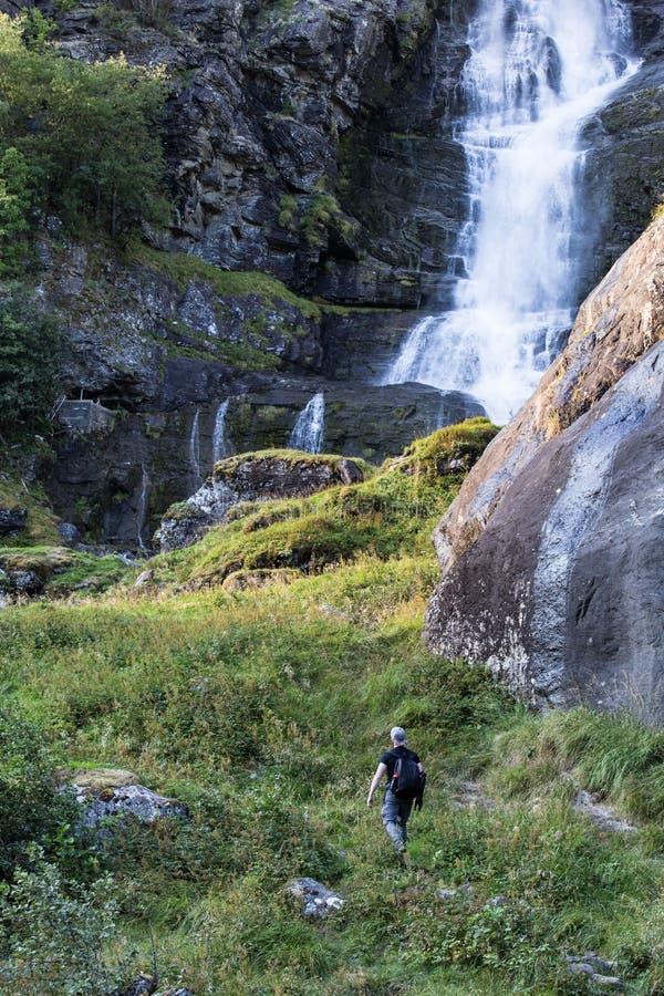 Wandelaar die met rugzak wandelen die waterval in park in het mooie landschap van de de herfstaard bekijken Portret van mannelijk stock fotografie Wandelaar die met rugzak wandelen die waterval in park in het mooie landschap van de de herfstaard bekijken Portret van mannelijk stock fotografie