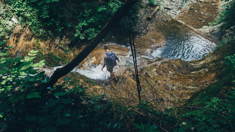Wanderer-Reisend-Forscher-Crosses Wild River-Wasserfall-Stützübungs-extremes Sport-Konzept stockfoto