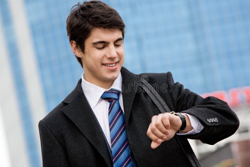 Photo of busy young man watching the time and smiling. Photo of busy young man watching the time and smiling