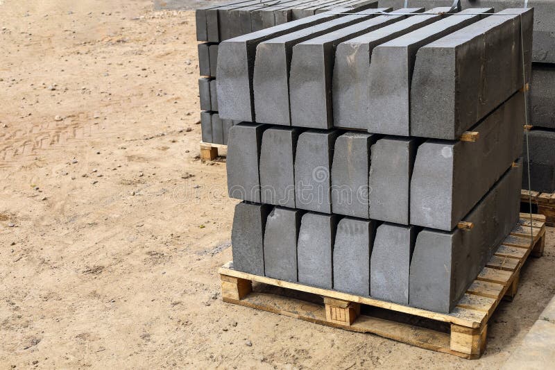 Warehouse of cement pressed materials on wooden pallets. Large pile of grey slabs and curbs for work at construction royalty free stock photography