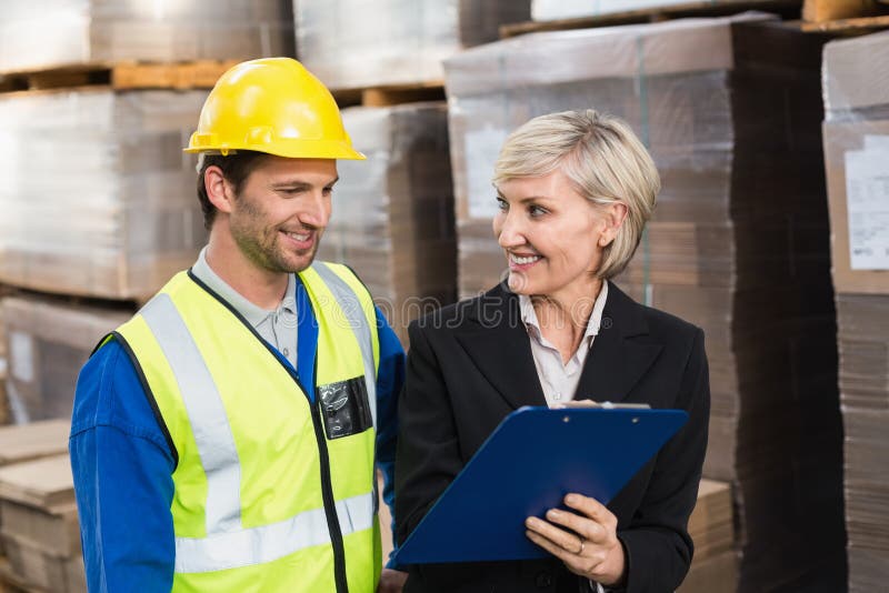 Warehouse manager showing clipboard to her colleague royalty free stock image