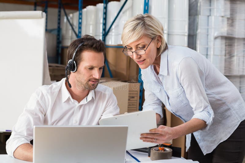 Warehouse manager showing something to her colleague stock photography