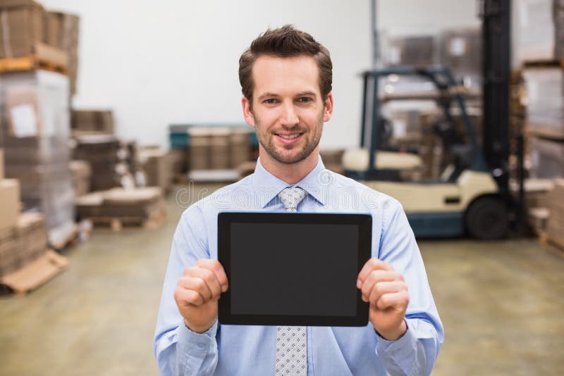 Warehouse manager showing tablet pc smiling at camera royalty free stock photos