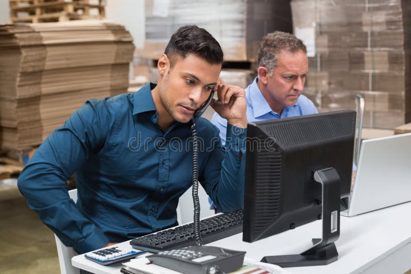 Warehouse managers using telephone and laptop stock photos