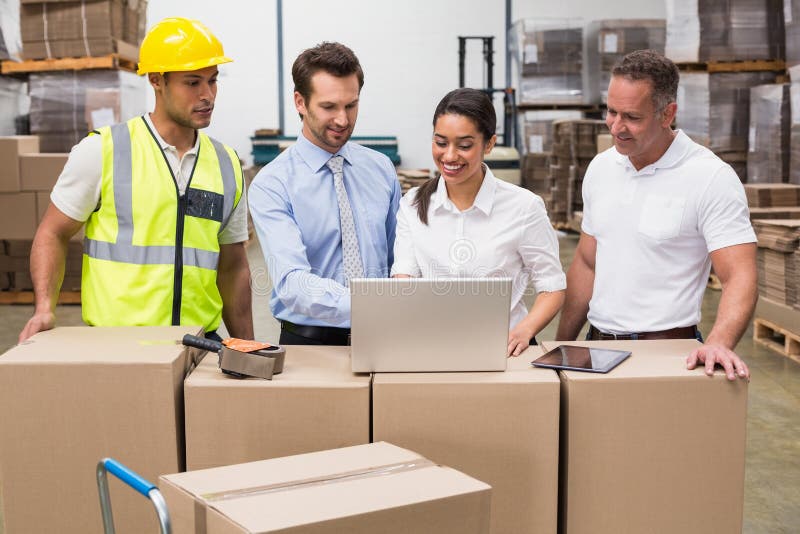 Warehouse managers and worker looking at laptop royalty free stock photo