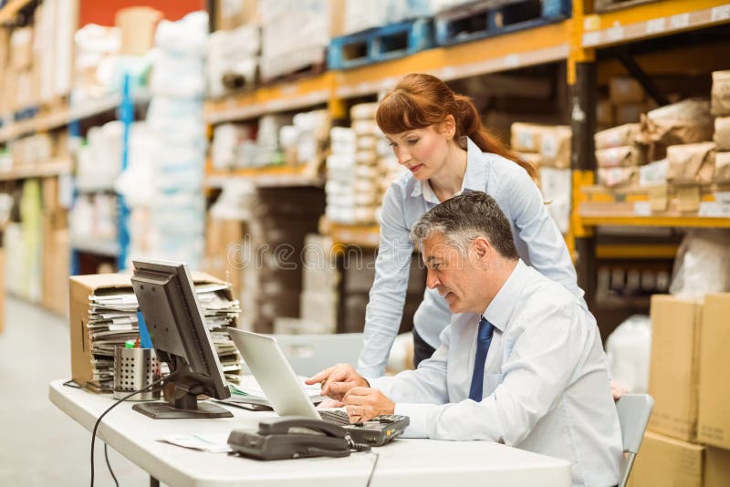 Warehouse managers working together on laptop stock photos