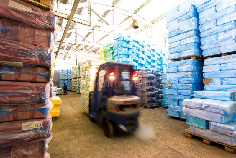 Warehouse with Riding Forklift and Stacks of Box at Factory Stock Photo