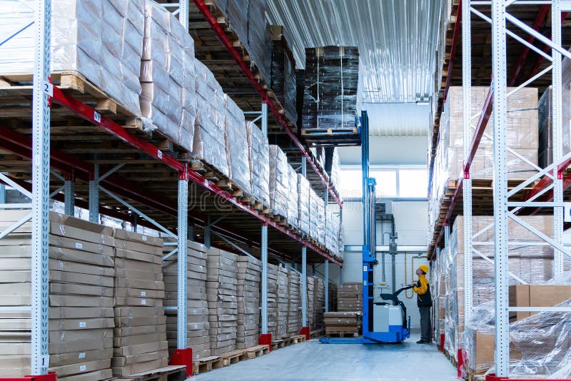 Warehouse worker driver in uniform delivery and loading cardboxes by forklift stacker loader royalty free stock photography Warehouse worker driver in uniform delivery and loading cardboxes by forklift stacker loader royalty free stock photography