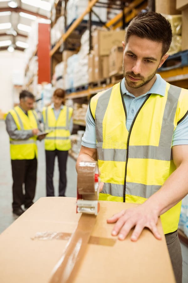 Warehouse Worker Sealing Cardboard Boxes for Shipping Stock Photo