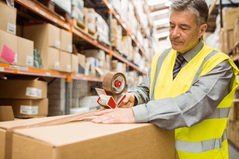 Warehouse Worker Sealing Cardboard Boxes for Shipping Stock Photo