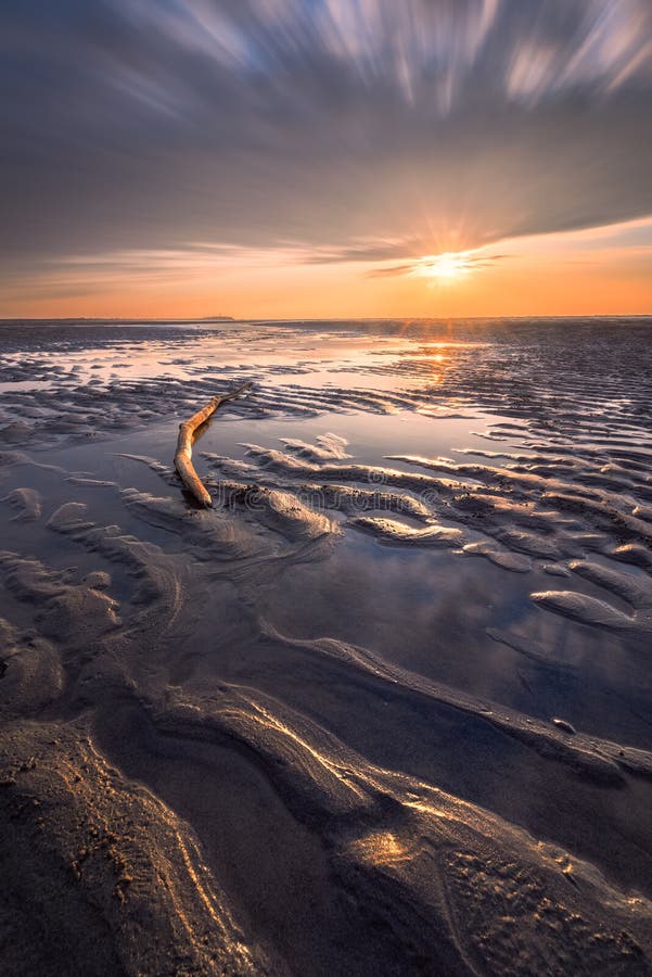 Warm afternoon sun rays on a beach at low tide in Taiwan with sand patterns and clouds passing stock photos