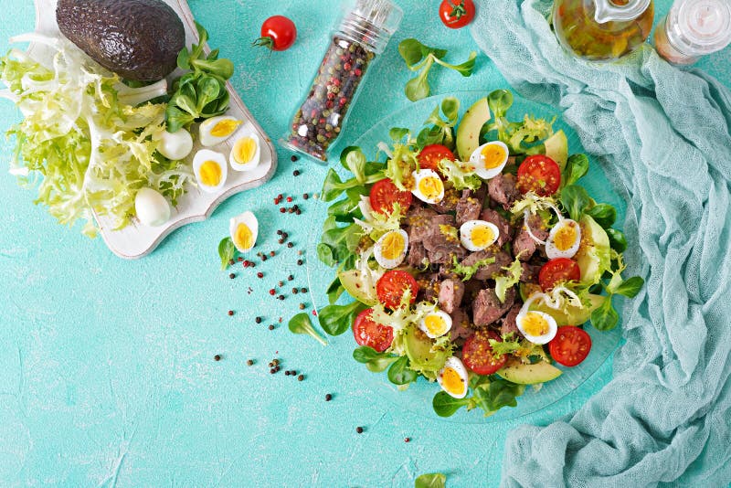 Warm salad from chicken liver, avocado, tomato and quail eggs. Healthy dinner. Dietary menu.