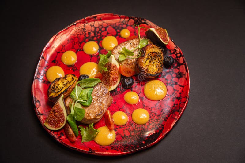 Warm salad, fried pork, fig slices, fried peaches, blueberries, cherry tomato slices, green leaves, pumpkin puree sauce. On a stock image Warm salad, fried pork, fig slices, fried peaches, blueberries, cherry tomato slices, green leaves, pumpkin puree sauce. On a stock image