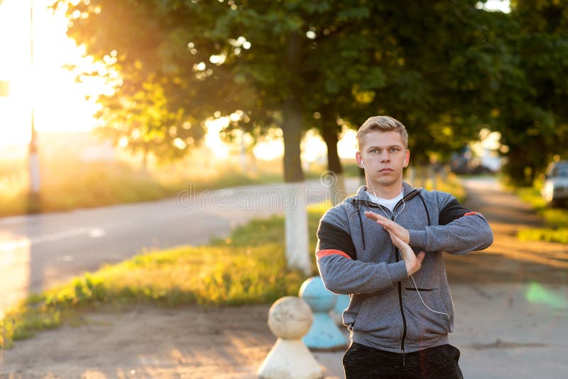 Warm-up hands, a young guy runner early in the morning doing the headphones. A man in the park listens to music, a