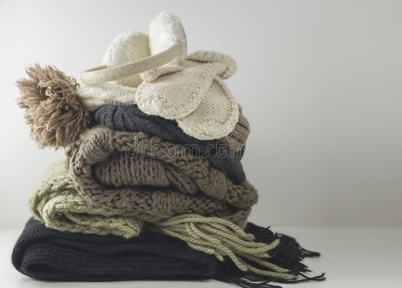 Warm woolen knitted winter and autumn clothes, folded in a pile on a white table. Sweaters, scarves, gloves, hat stock photography Warm woolen knitted winter and autumn clothes, folded in a pile on a white table. Sweaters, scarves, gloves, hat stock photography