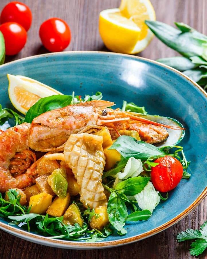 Warme salade met zeevruchten, langoustine, mosselen, garnalen, pijlinktvis, kammosselen, mango, ananas, avocado stock afbeeldingen Warme salade met zeevruchten, langoustine, mosselen, garnalen, pijlinktvis, kammosselen, mango, ananas, avocado stock afbeeldingen