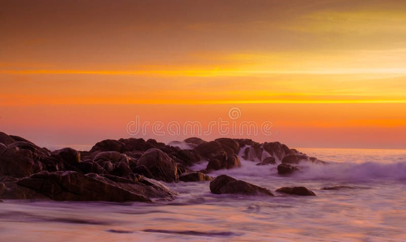 Warme zonsondergang over de rotsen in water van oceaan stock afbeeldingen Warme zonsondergang over de rotsen in water van oceaan stock afbeeldingen