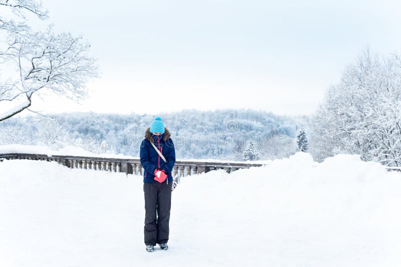 Warmly clothed freezing girl on snowy frozen woodland background