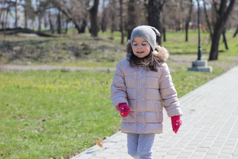 Warmly Dressed Little Girl in Mittens Runs in the Park Stock Image