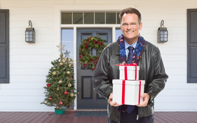 Warmly Dressed Man Holding Gifts Standing on Christmas Decorated Front Porch