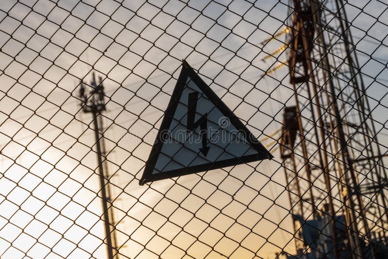 Warnendes dreieckiges Zeichen mit einem Blitzbild auf dem Nettozaun Gefährlich - Hochspannungs Elektrische Nebenstelle lizenzfreie stockbilder Warnendes dreieckiges Zeichen mit einem Blitzbild auf dem Nettozaun Gefährlich - Hochspannungs Elektrische Nebenstelle lizenzfreie stockbilder