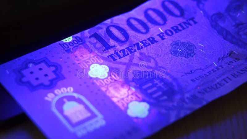 Warsaw, Poland 01.01.2021 Hungarian forint UV lamp anti-counterfeiting test. Luminescent ink patterns got visible under