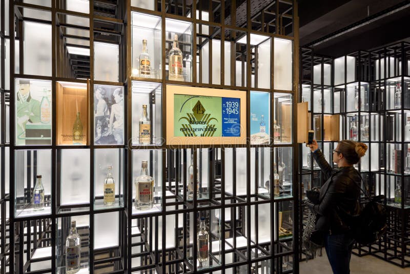 Warsaw Vodka Museum. Warsaw, Poland - Oct 20, 2018: A visitor taking a picture of old Vodka bottles in the Warsaw Vodka Museum stock photo Warsaw Vodka Museum. Warsaw, Poland - Oct 20, 2018: A visitor taking a picture of old Vodka bottles in the Warsaw Vodka Museum stock photo