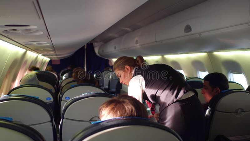 WARSCHAU, POLEN - DEZEMBER, 24 VERLOSEN Sie weiblichen Flugbegleiter an den Arbeits- und Passagierflugzeugpassagieren in der Kabi stockbild WARSCHAU, POLEN - DEZEMBER, 24 VERLOSEN Sie weiblichen Flugbegleiter an den Arbeits- und Passagierflugzeugpassagieren in der Kabi stockbild