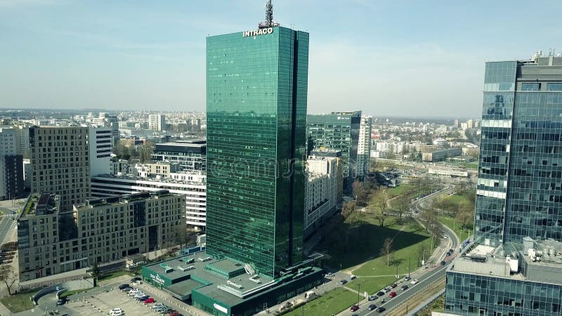 WARSZAWA POLEN - APRIL, 1, 2017 Antennskott av modern kontorsbyggnad med reflekterande cityscape för INTRACO-överskrift på a royaltyfri fotografi WARSZAWA POLEN - APRIL, 1, 2017 Antennskott av modern kontorsbyggnad med reflekterande cityscape för INTRACO-överskrift på a royaltyfri fotografi